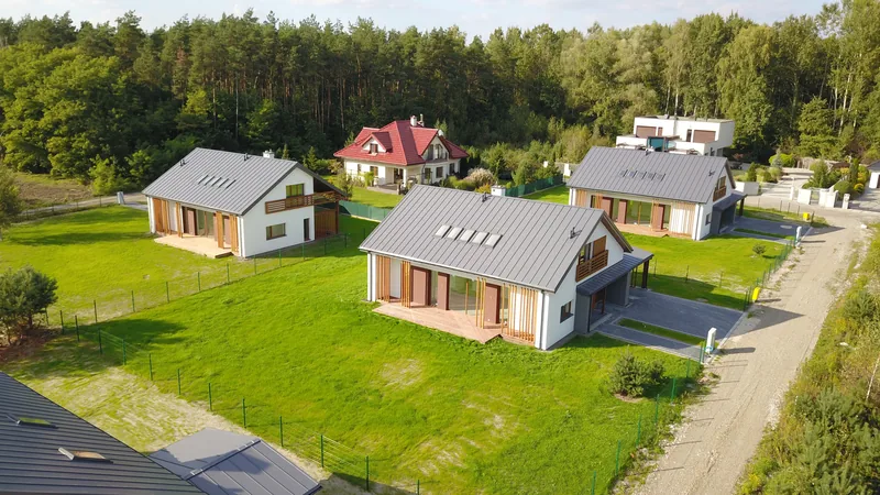Drone shot pięciu nowoczesnych domów jednorodzinnych z drewnianymi elewacjami i dwuspadowymi dachami, ukończona realizacja